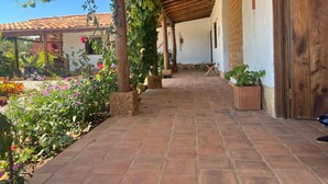 A covered outdoor area with a tiled floor, potted plants, and a wooden pergola. - CASA MORANESI (Caucasia)