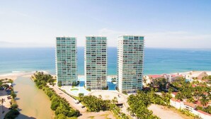 A high-rise hotel with multiple floors, a pool area, and a beach view. - Península T3 1A Luxurious Ocean View Getaway! (Puerto Vallarta)