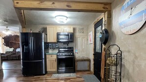Una cocina con armarios de madera, un refrigerador negro, un microondas y una estufa.