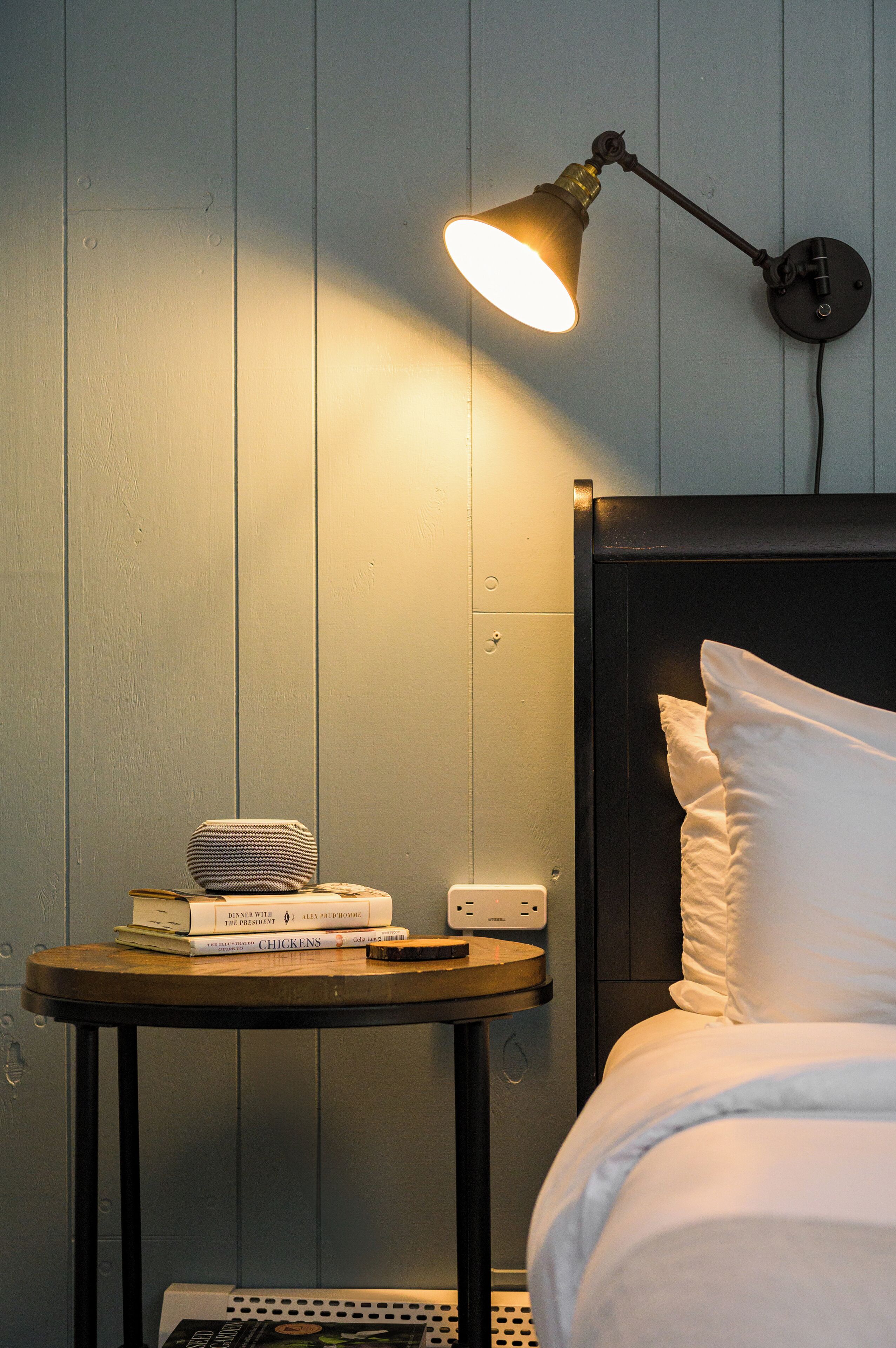 A neatly made bed with white linens, a bedside table with a lamp, and a few books.