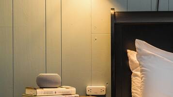 A neatly made bed with white linens, a bedside table with a lamp, and a few books.