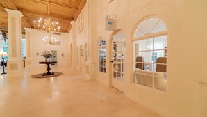 Un pasillo espacioso con techo de madera, ventanas arqueadas y un candelabro.