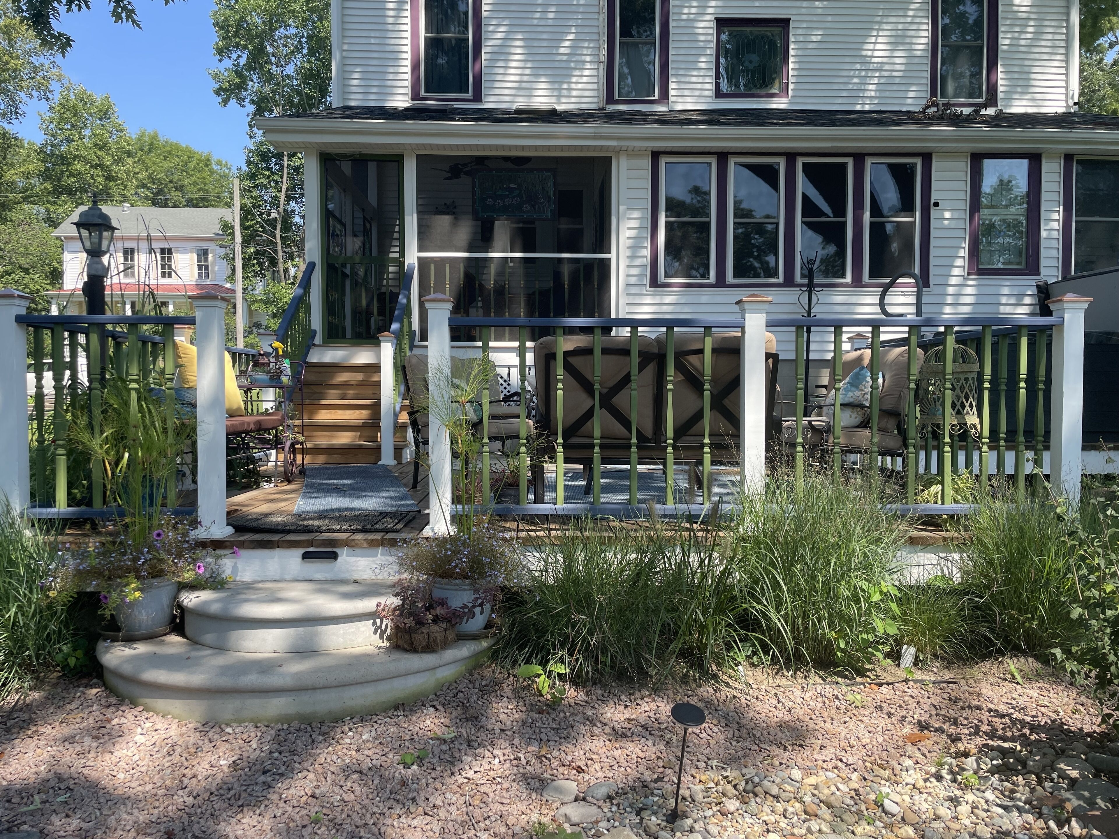 A two-story house with a porch, steps, and outdoor seating.