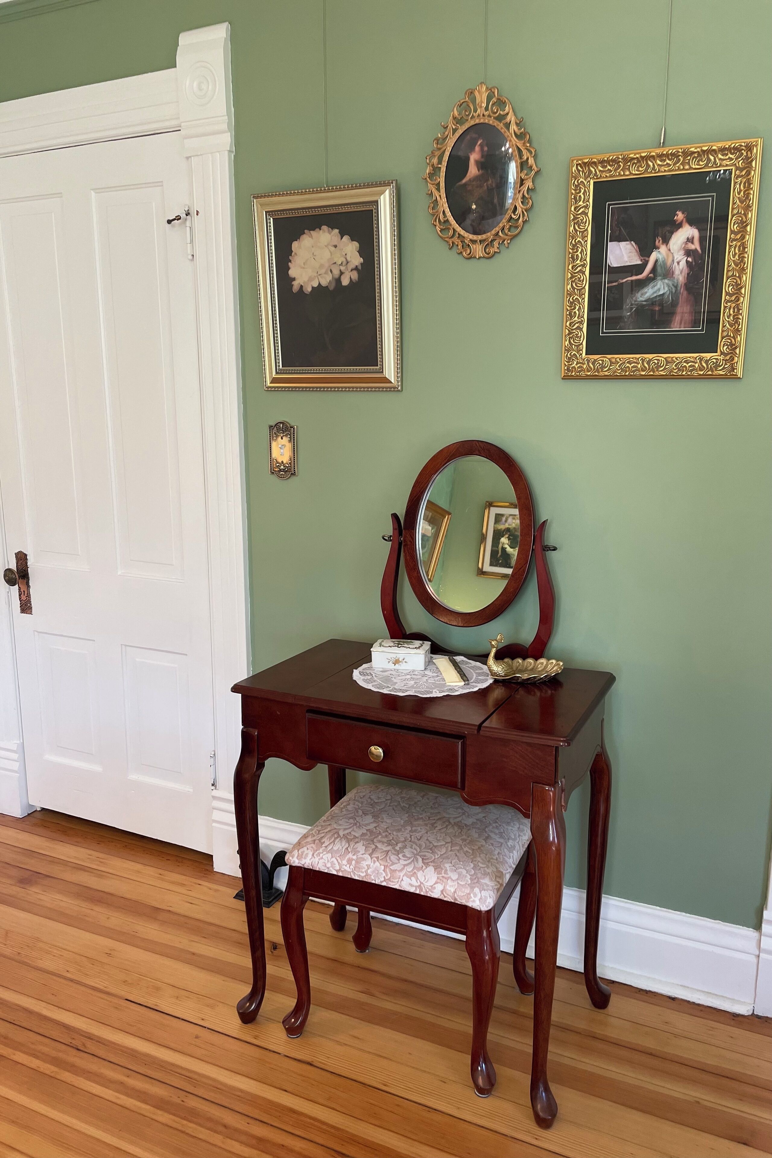 A room with a wooden vanity, a mirror, and framed pictures on the wall.