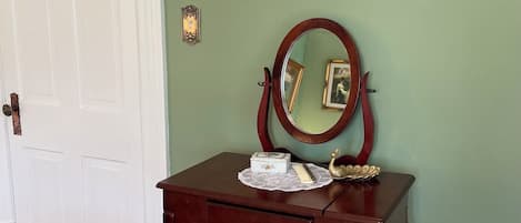 A room with a wooden vanity, a mirror, and framed pictures on the wall.