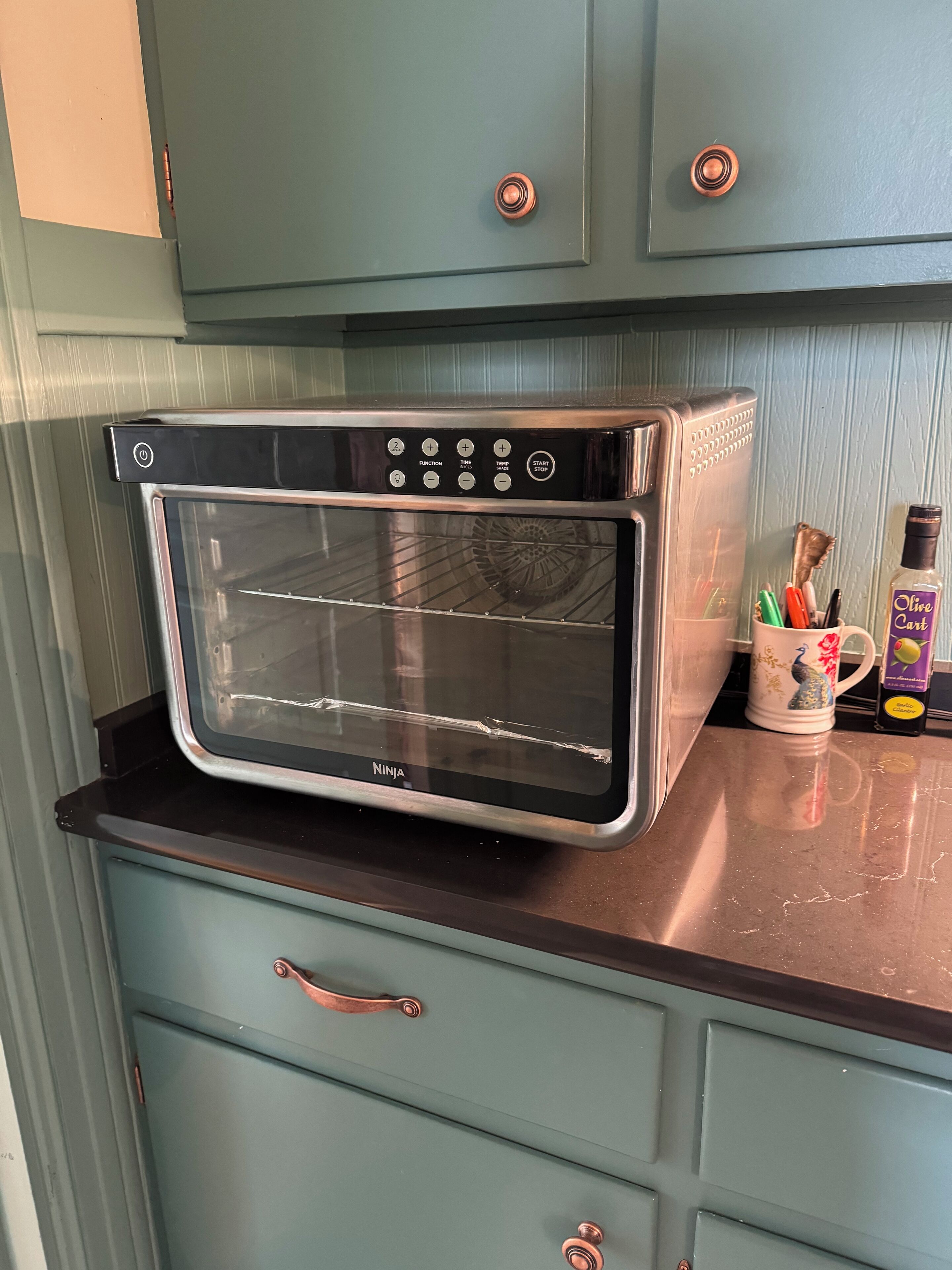 A kitchen with a built-in oven, a coffee maker, and a mug on the counter.
