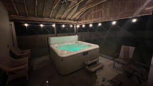 A hot tub in a rustic room with wooden beams, a ceiling fan, and string lights. - Close to Town, Hot Tub, 2 Kings, 4 Full Beds (Old Forge)