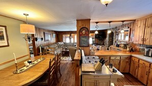 A cozy, wood-paneled interior with a dining area, kitchen, and seating space. - Close to Town, Hot Tub, 2 Kings, 4 Full Beds (Old Forge)