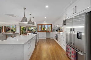 Enjoy cooking in this well-equipped kitchen with a central island, stainless steel appliances, and a large window offering a view of the outdoors.