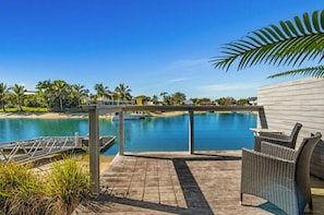 Relax by the pool surrounded by a wooden deck and palm trees.