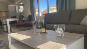 A modern living room with a wooden coffee table, a bottle of champagne, and two wine glasses.