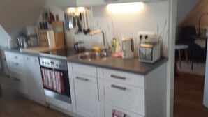 Una cocina con gabinetes blancos, estufa y lavaplatos.