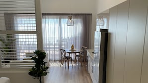 Moderni keittiö, jossa on puulattia, ruokailutila pyöreällä pöydällä ja tuoleilla sekä sisäänrakennettu jääkaappi.