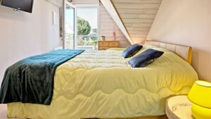A bedroom with a bed, a TV mounted on the wall, and a view of the outdoors through a sliding door.