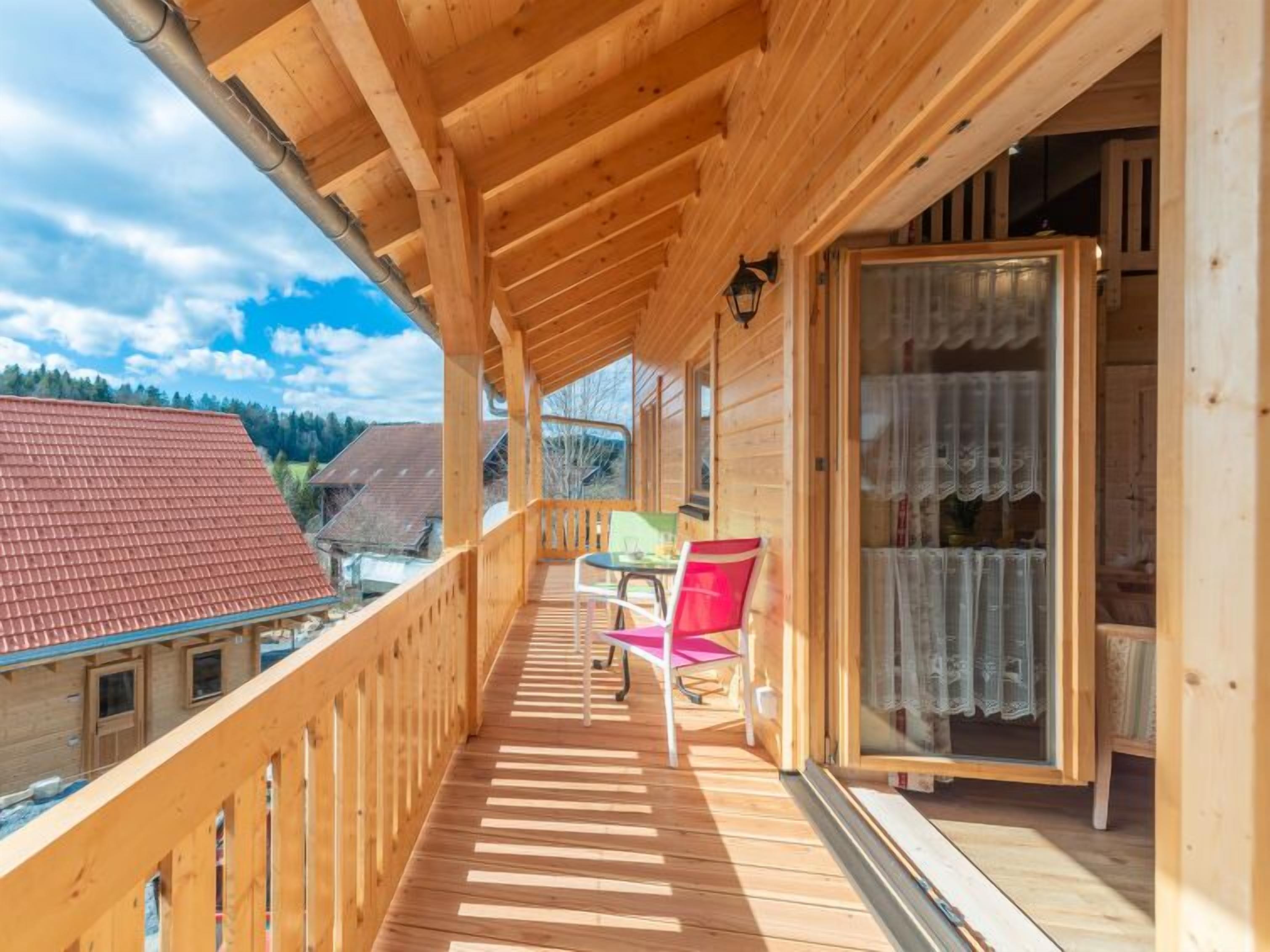 A wooden balcony with a view of the surrounding buildings and a clear sky.