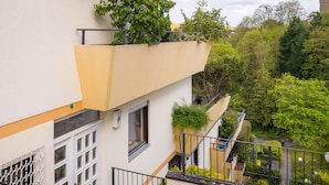Un edificio moderno con un diseño arquitectónico único, que presenta un techo inclinado y un balcón con plantas.