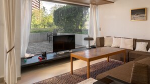 Una sala de estar moderna con un televisor de pantalla plana, una mesa de centro de madera y un sofá.