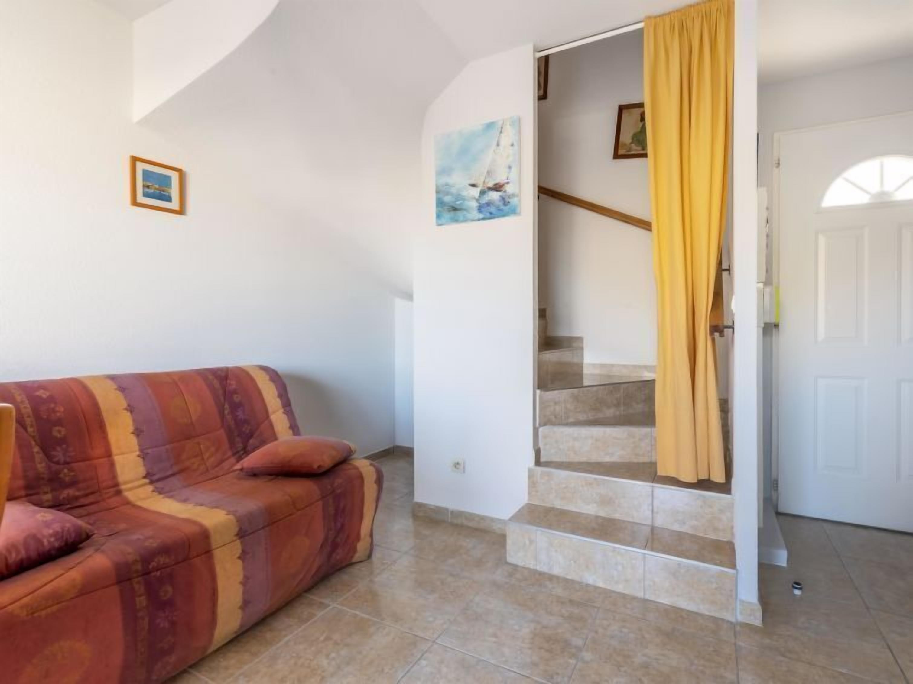 A living room with a sofa, a staircase, and a door with a yellow curtain.