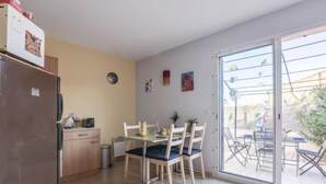 Uma cozinha compacta com geladeira, um pequeno balcão e um espaço de refeições com mesa e cadeiras.