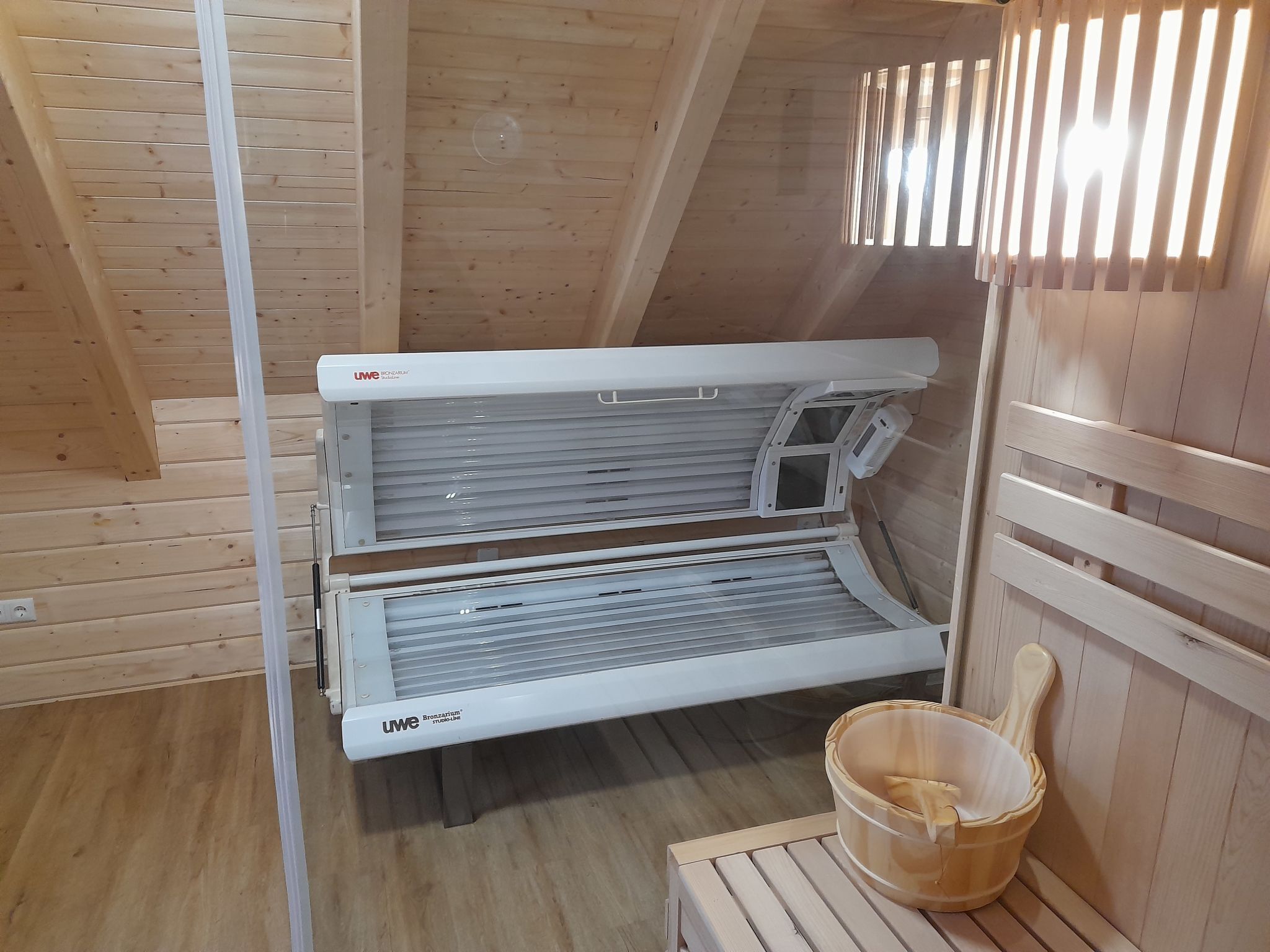 Un sauna avec un intérieur en bois, un banc et un seau.