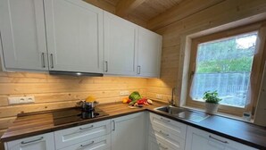 Une cuisine moderne avec des meubles blancs, un plan de travail en bois et une fenêtre donnant sur un paysage verdoyant.