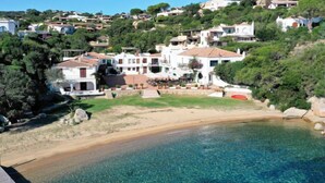 Un quartier résidentiel en bord de mer, avec des maisons construites sur une colline, une plage de sable fin et une piscine.