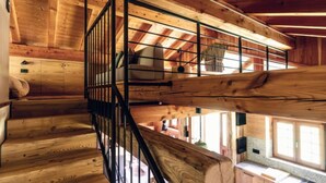 Un intérieur en bois avec un escalier en colimaçon et une chambre à coucher située en mezzanine.