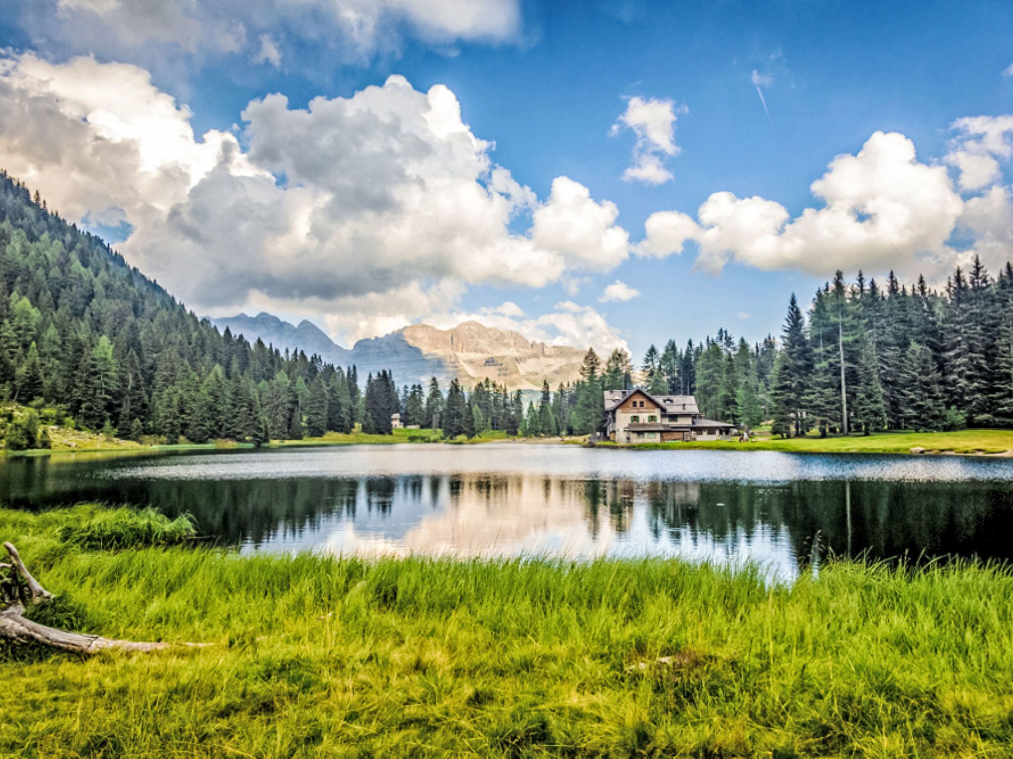 A lakeside cabin with a view of mountains and a clear sky.