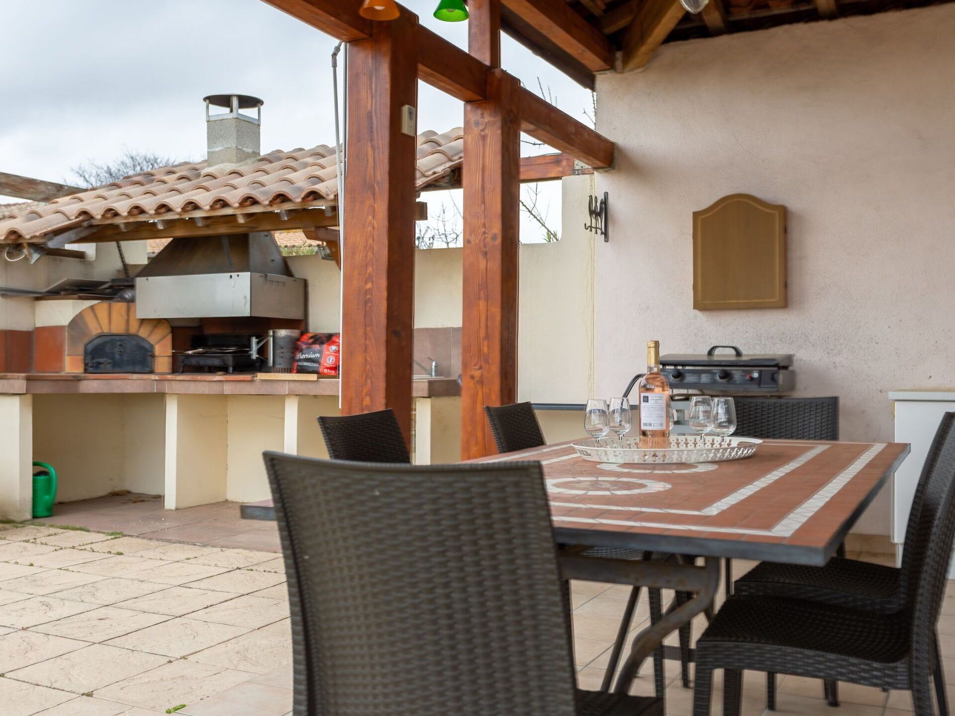 Een terras buiten met een barbecue, eettafel en stoelen.