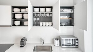 Une cuisine moderne avec des meubles blancs, un évier en acier inoxydable, un grille-pain et un four à micro-ondes.