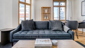 Un salon moderne avec un canapé gris, une table basse en bois et une bibliothèque.