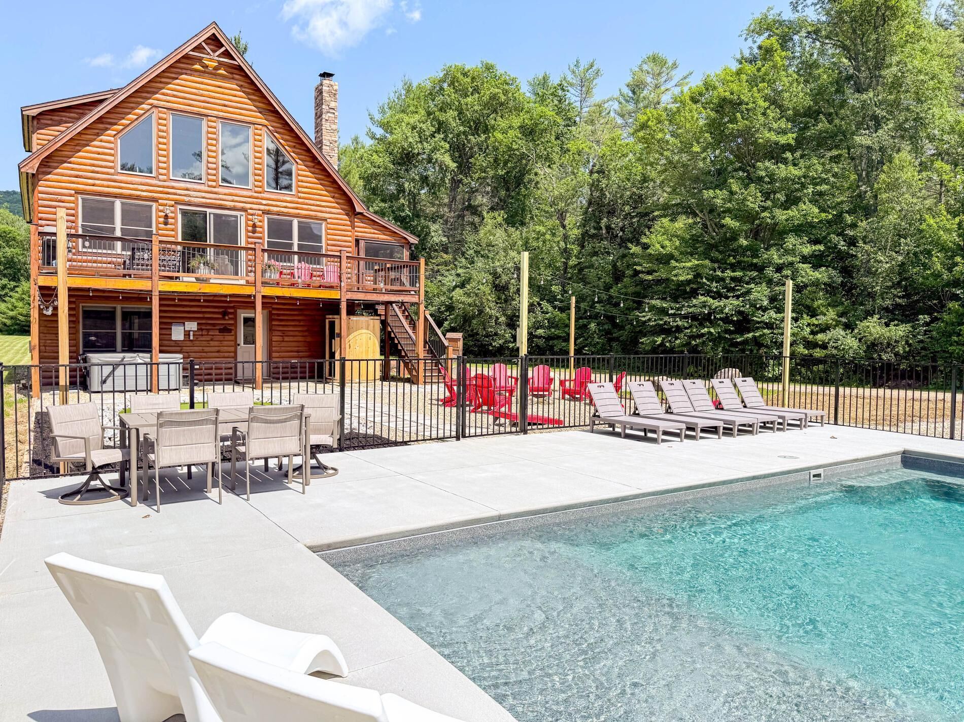Une cabane en rondins avec une piscine, un espace salon extérieur et une aire de jeux.