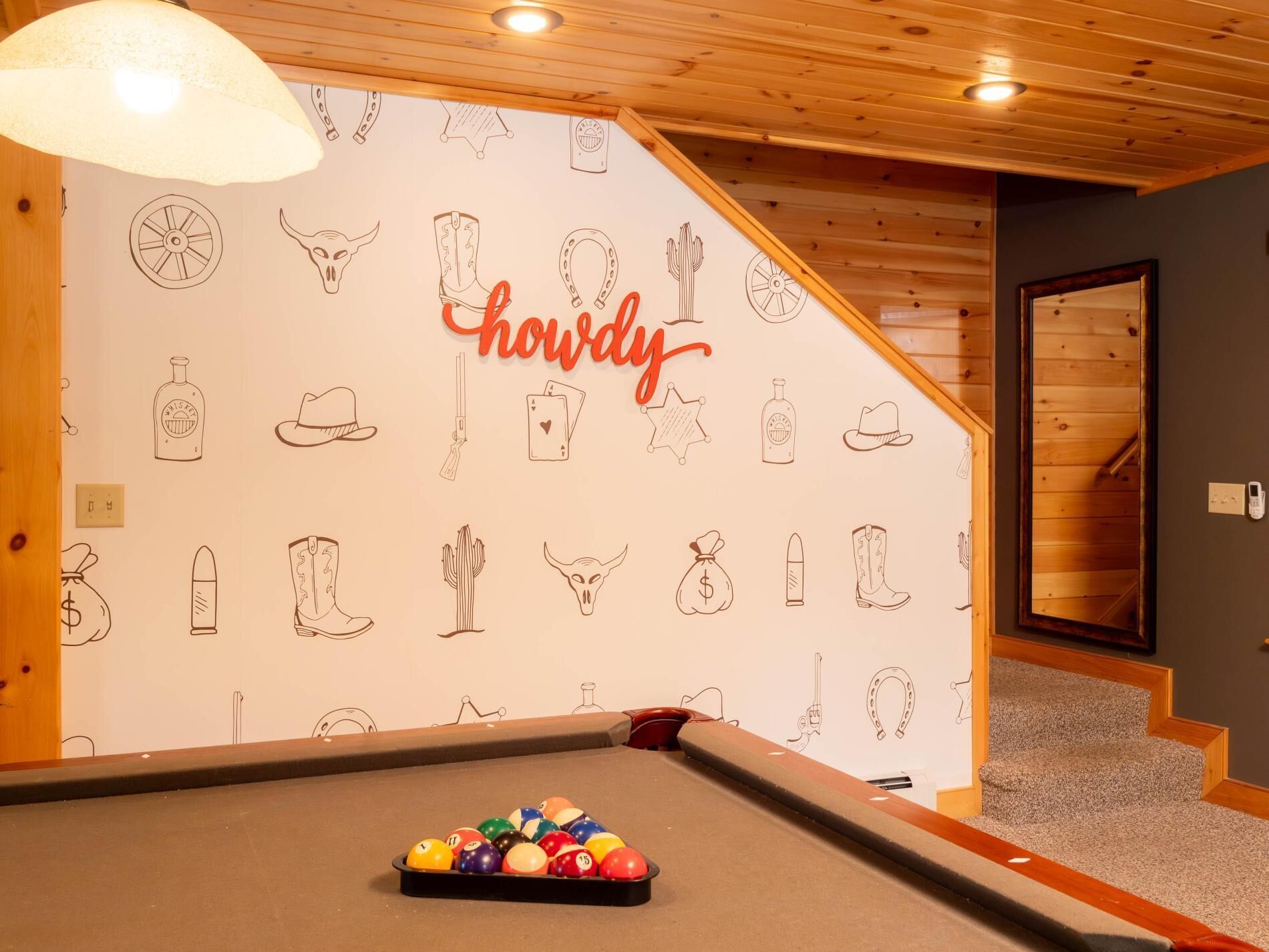 Ein Billardtisch mit Wandgemälde, das verschiedene Objekte und den Schriftzug 'howdy' zeigt.