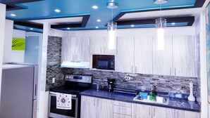 Una cocina moderna con cubierta de color negro, electrodomésticos de acero inoxidable y techo azul.