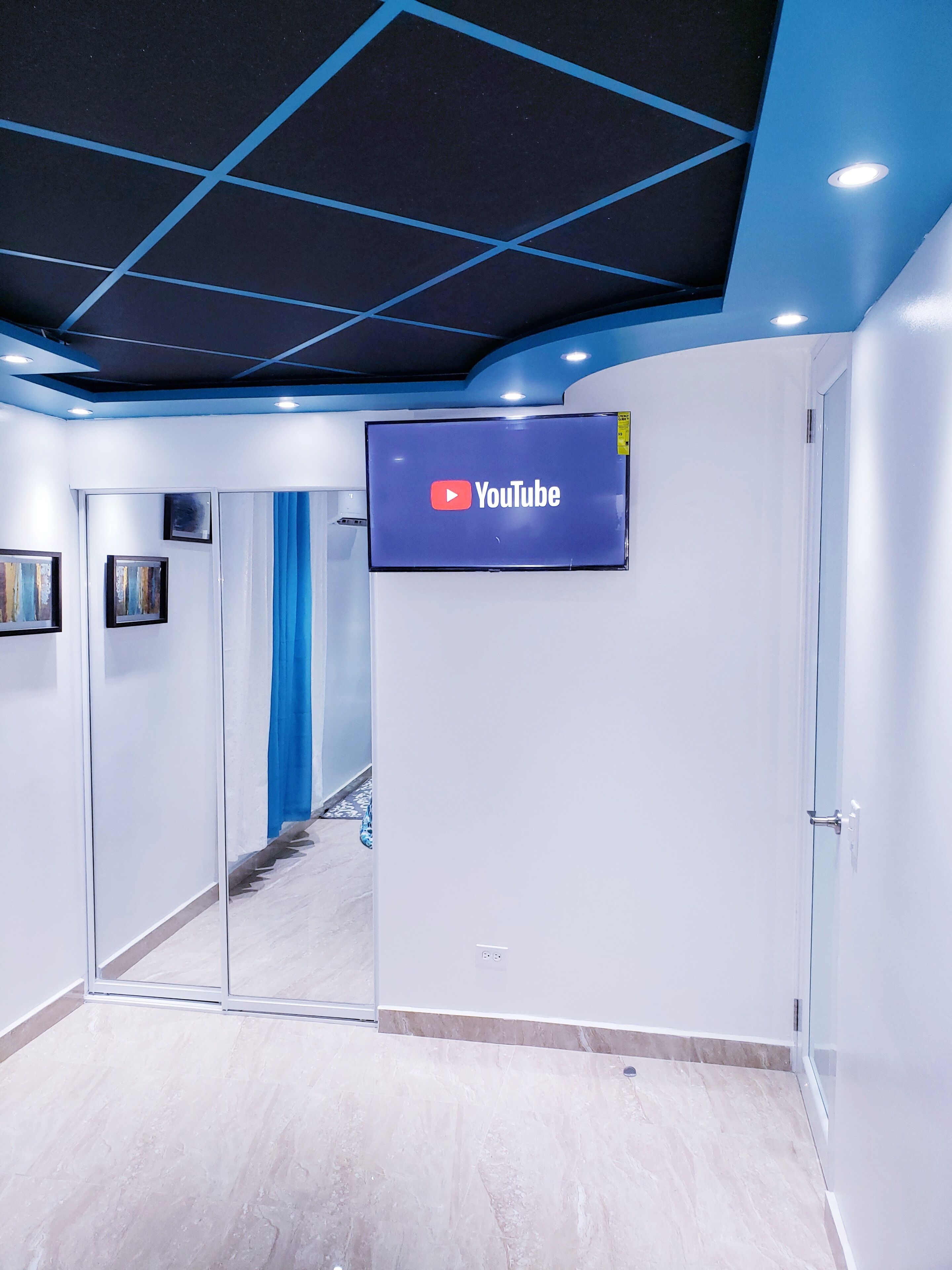 A modern interior with a YouTube logo on a screen, a glass door, and a blue curtain.