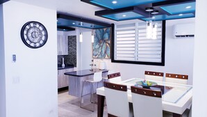 Un comedor moderno con una mesa de vidrio, sillas de madera y un reloj en la pared.