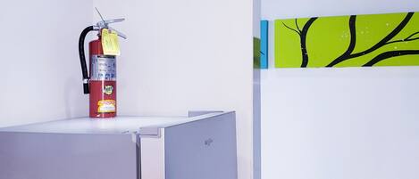 Una cocina moderna con un refrigerador de acero inoxidable, un extintor en la encimera y una pared con diseño de rama de árbol.