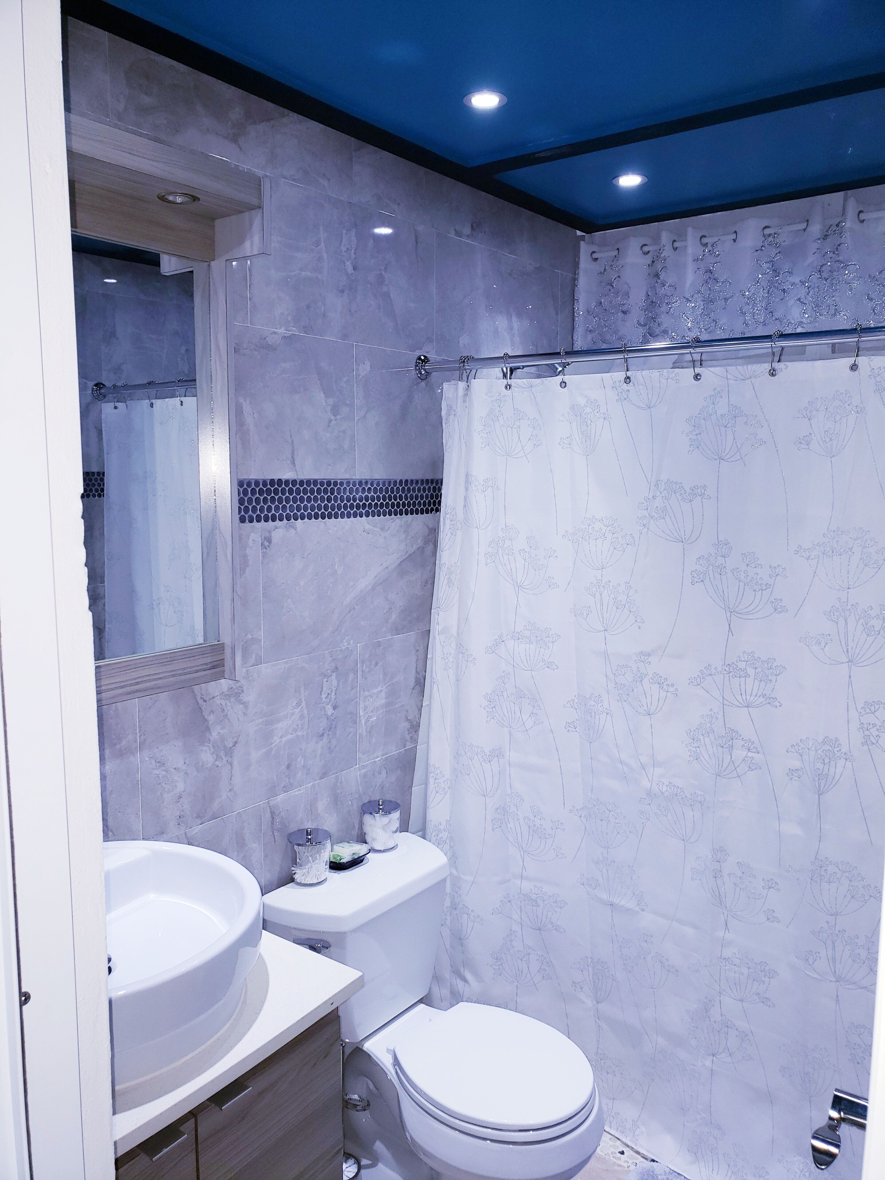 A modern bathroom with a white toilet, a sink, and a shower curtain with floral patterns.