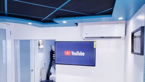 Una habitación moderna con el logotipo de YouTube en la pared, un mueble de almacenamiento negro y un equipo de aire acondicionado blanco.