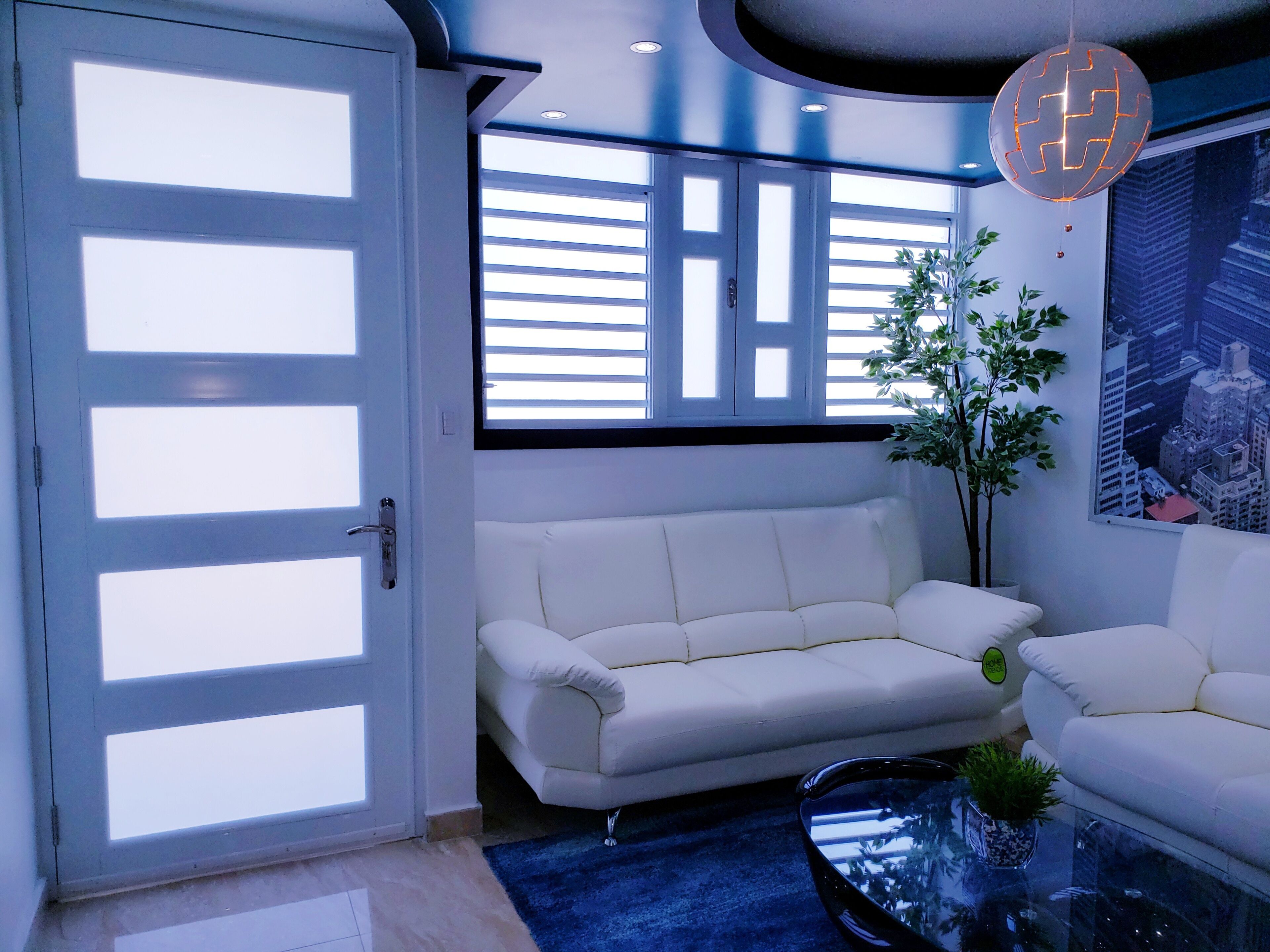 Una sala de estar moderna con un sofá blanco, una mesa de centro de vidrio y una planta en maceta.