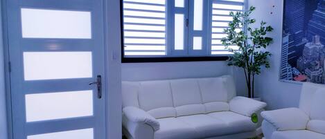 Una sala de estar moderna con un sofá blanco, una mesa de centro de vidrio y una planta en maceta.