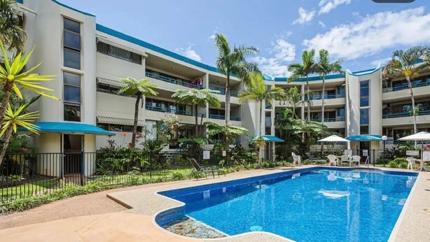 Un hôtel doté d’une piscine, de plusieurs balcons et de palmiers.