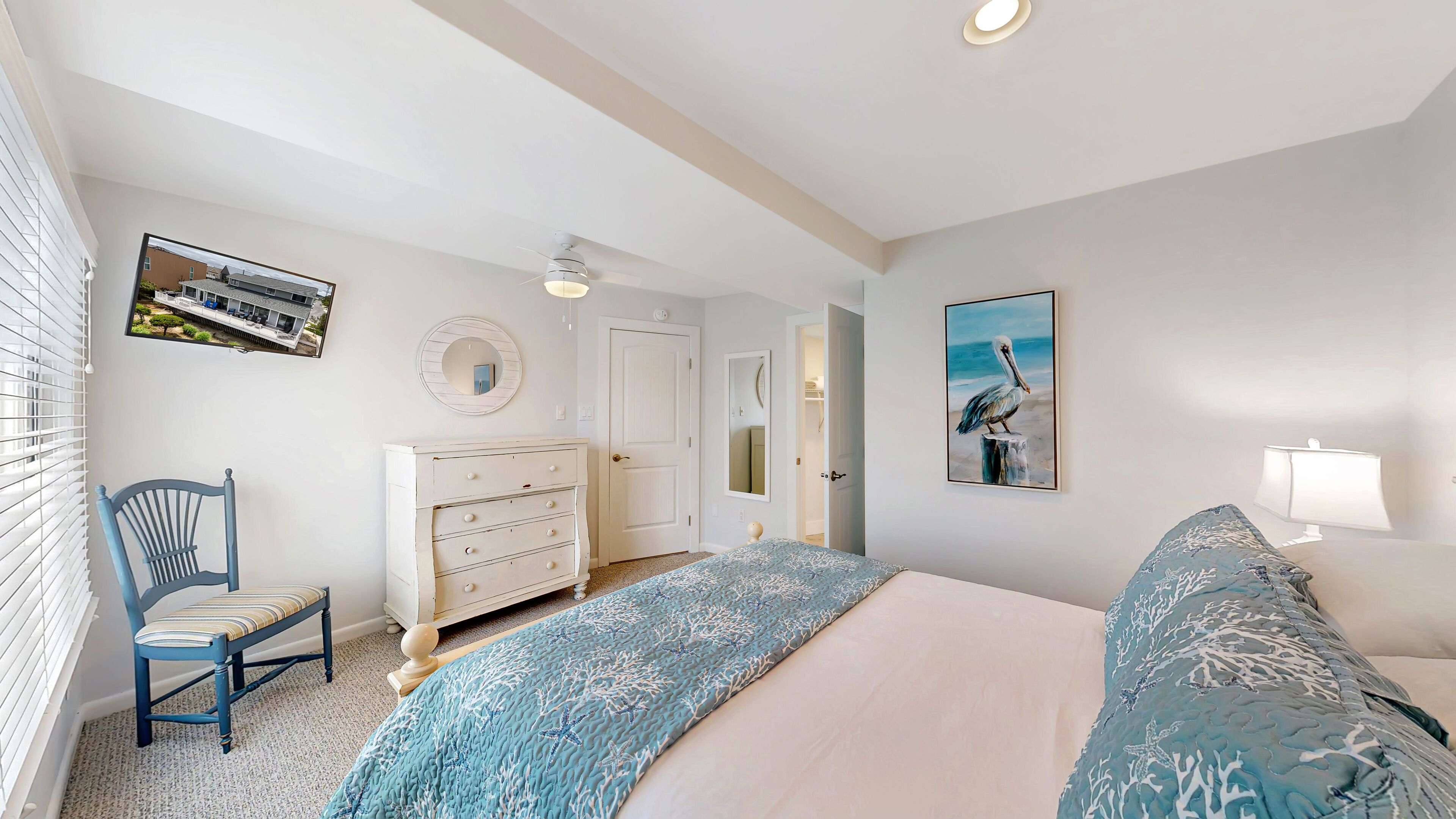 A bedroom with a bed, a dresser, a chair, a painting, and a window with blinds.