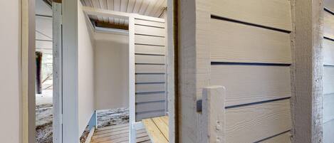 A wooden staircase leading to a lofted area with a sloped ceiling and a door with horizontal paneling.