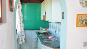 A narrow kitchen with green blinds, a sink, and a stove. - La Padula three-room first-floor apartment with furnished balcony in San Teodoro (San Teodoro)