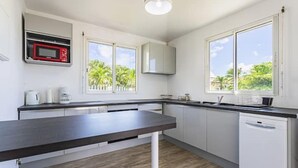 Une cuisine moderne avec des meubles blancs, un plan de travail foncé, un four à micro-ondes et un lave-vaisselle.