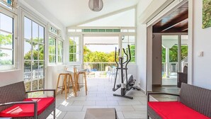 Un espace intérieur spacieux avec un patio, du matériel d’exercice et des meubles en osier.