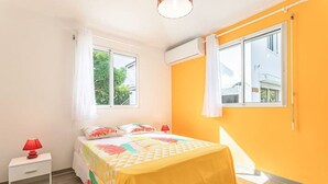 Une chambre à coucher comprenant un lit, une table de chevet, une fenêtre et un appareil de climatisation.