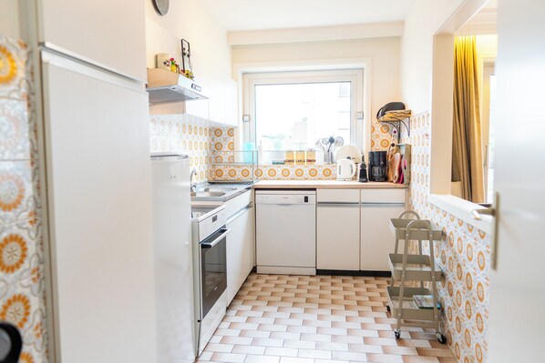 A kitchen with white cabinets, a dishwasher, a stove, and a window.