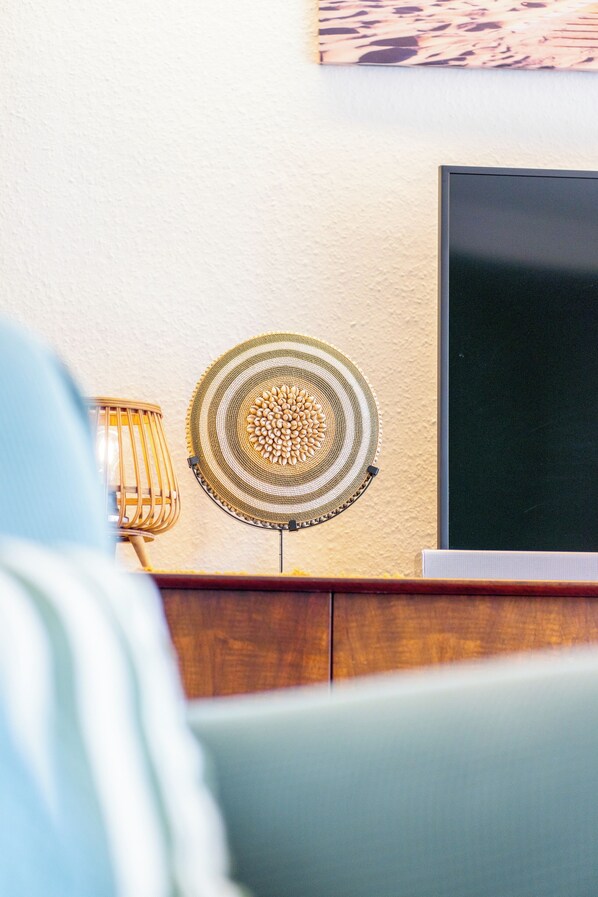 Een kamer met een televisie op een standaard, een decoratieve ventilator en een lamp op een houten oppervlak.